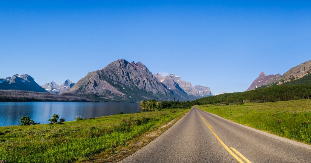 Scenic road next to a lake with a mountain in the background representing MT 200